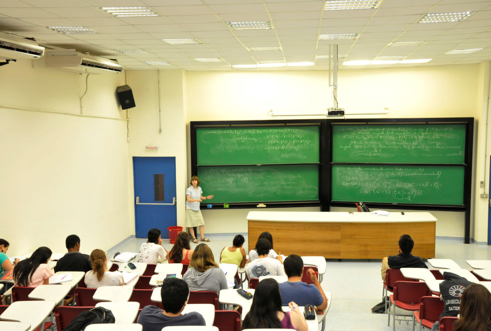 foto mostra sala de aula do ciclo básico, com os alunos sentados em primeiro plano e o professor ao fundo à lousa