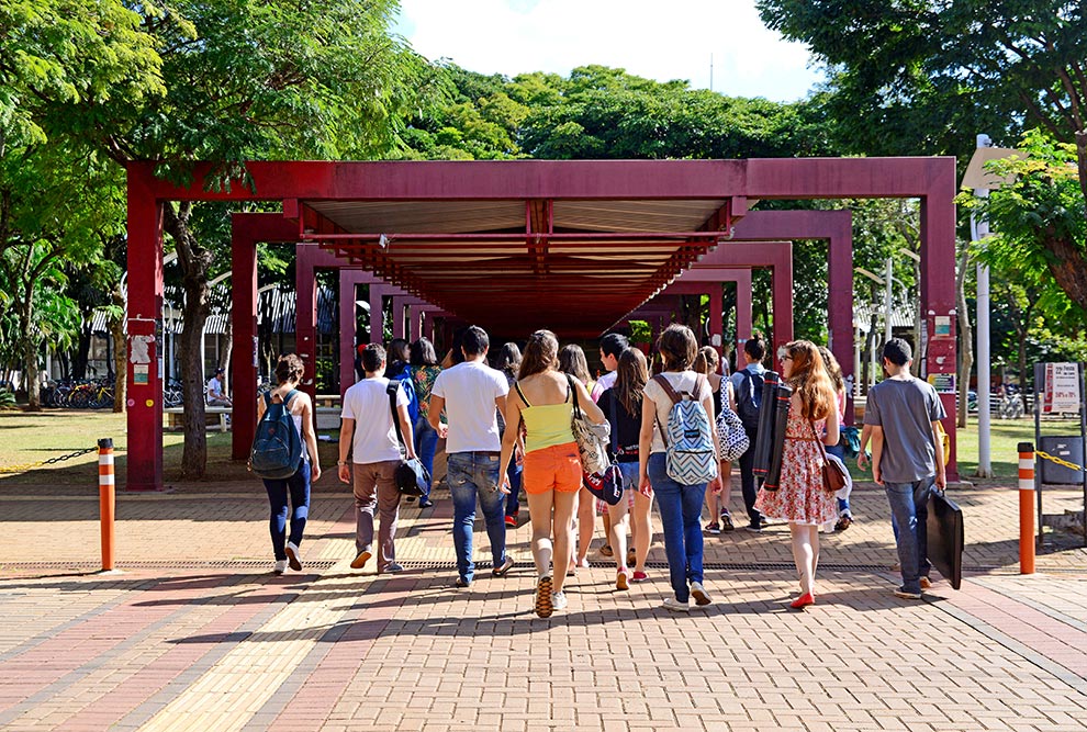 audiodescrição: fotografia colorida de estudantes caminhando no campus