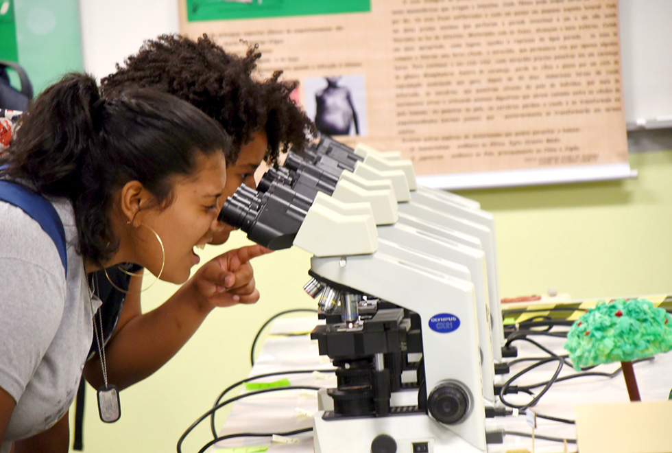 Estudantes olham em microscópio