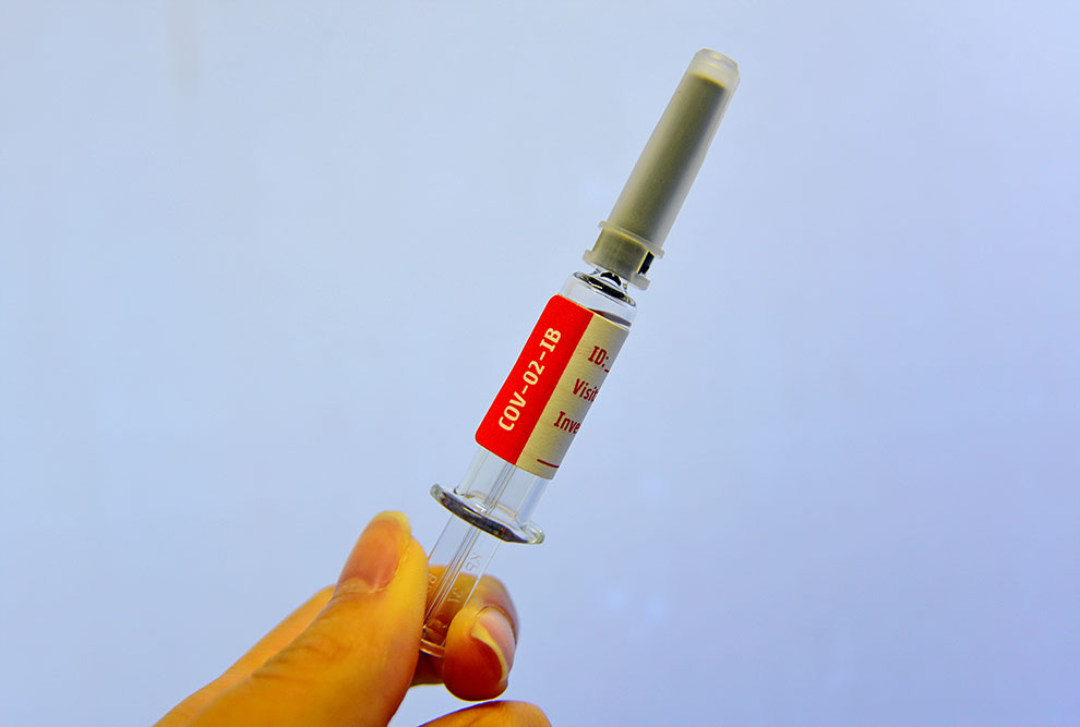 foto mostra uma mão segurando uma seringa com dose de vacina