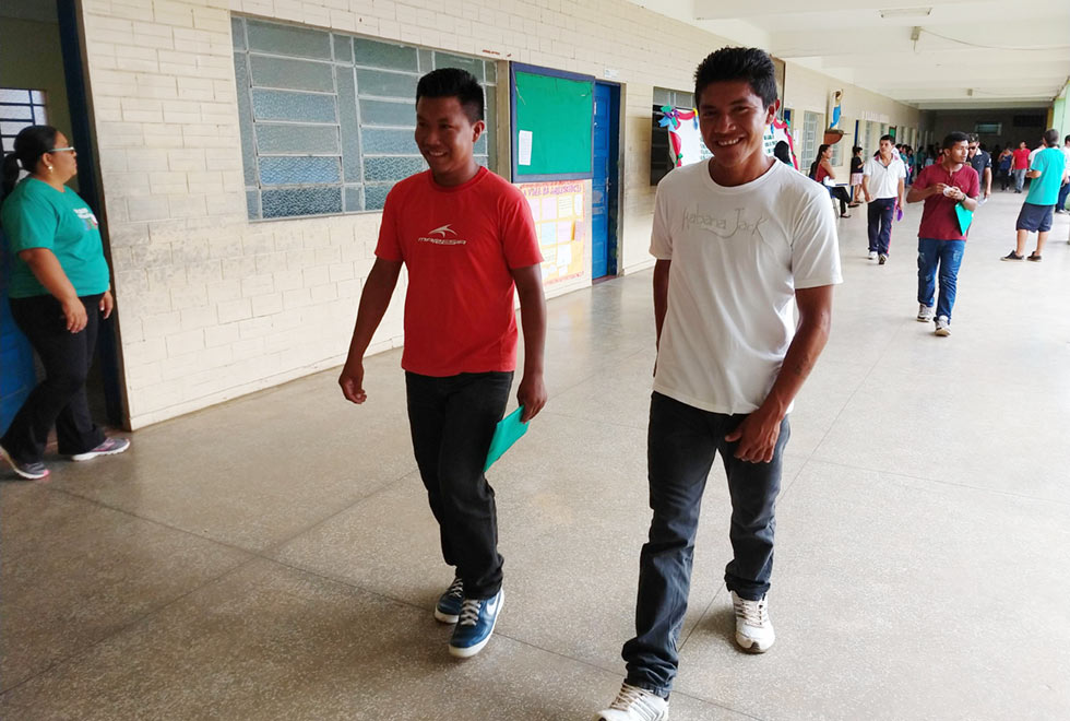 indígenas caminham em corredor de escola