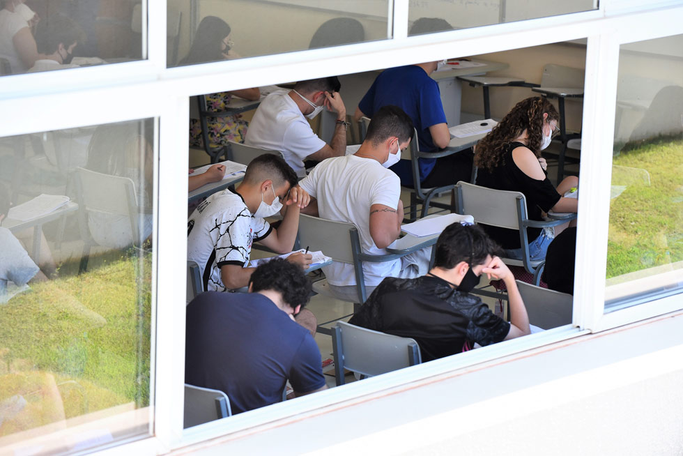 audiodescrição: fotografia colorida de estudantes realizando a prova em uma sala; todos estão de máscara e  concentrados realizando o exame