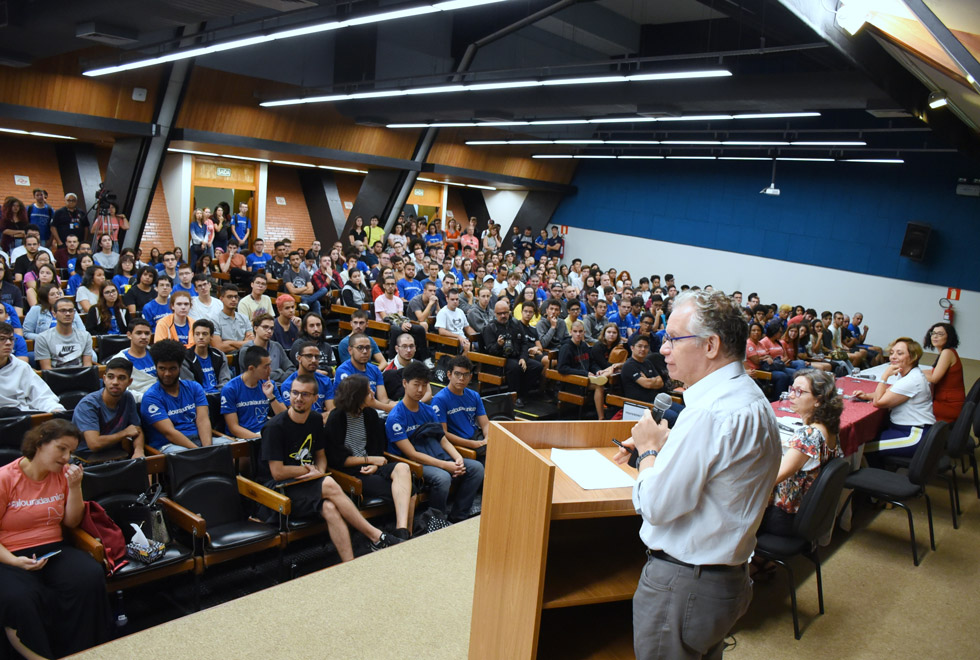 foto mostra auditório do centro de convenções cheio de alunos e do reitor marcelo knobel à frente