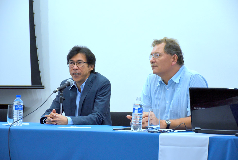 Célio Hiratuka está falando ao lado de outro convidado, na mesa de abertura do seminário