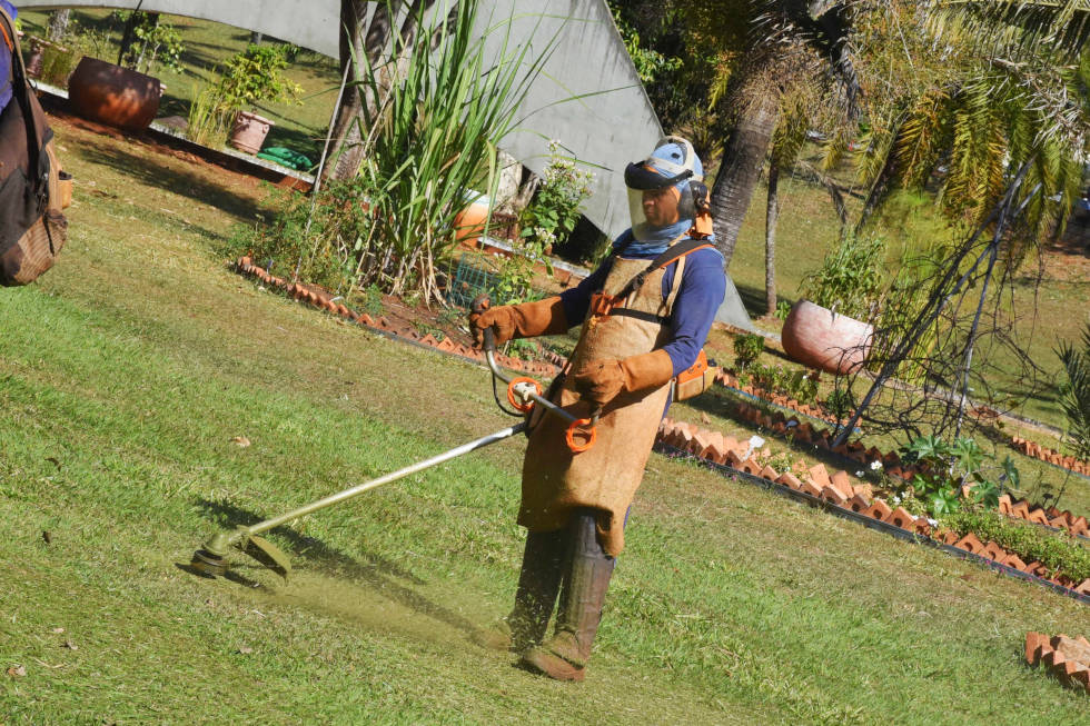 Trabalhador faz manutenção em área gramada da Unicamp