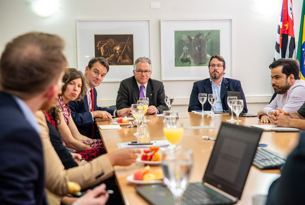 Foto mostra cena descontraída da reunião com foco no reitor que demonstra satisfação