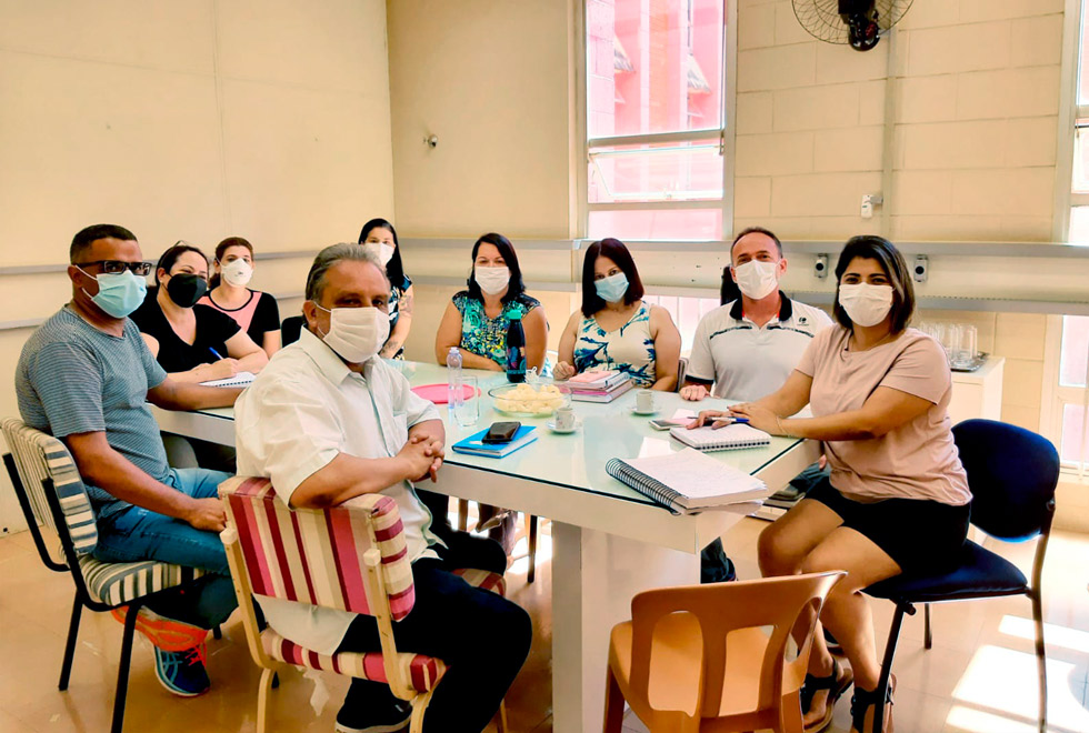 audiodescrição: fotografia colorida de uma mesa de reuniões e ao entorno dela membros da dedic e da educorp, todos usam máscara e posam para a foto