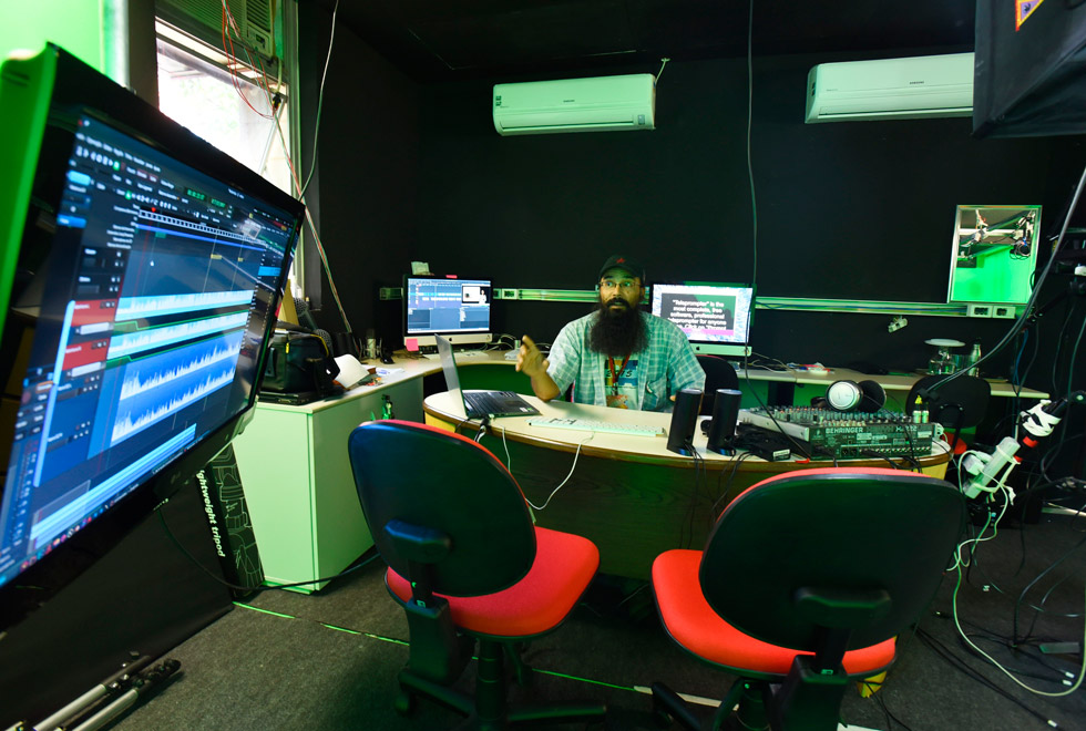 Imagem mostra estúdio de gravação do GGTE com funcionário atrás de uma mesa