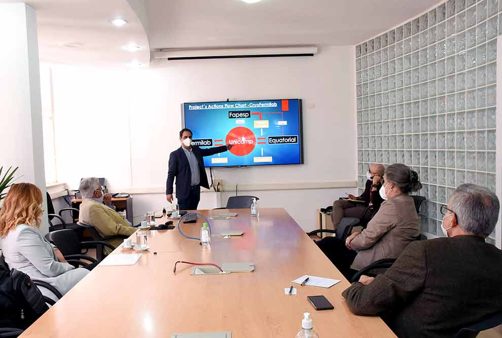 foto mostra uma mesa de reuniões com as pessoas sentadas acompanhando, ao fundo, pascoal pagliuso apresentando