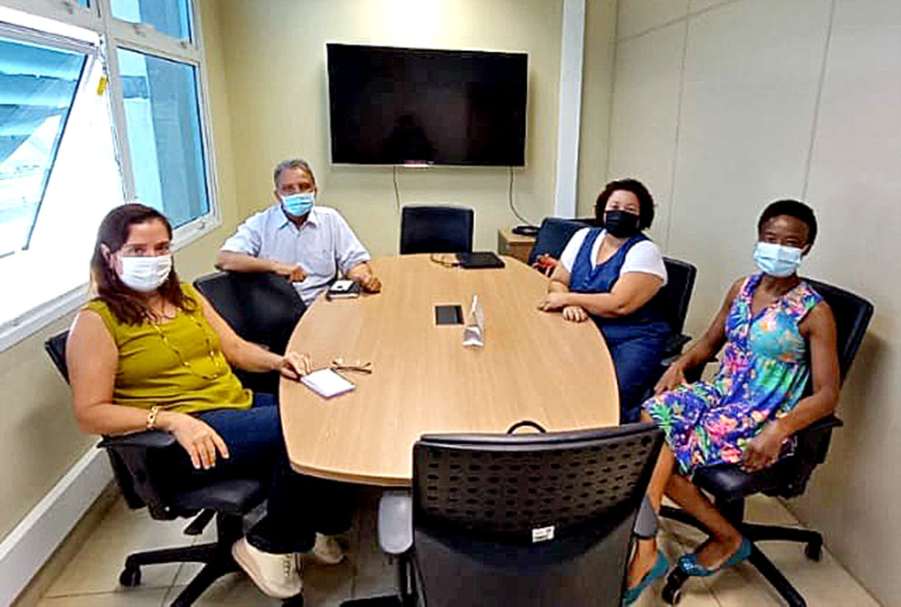 foto mostra servidoras com integrantes da educorp sentados em uma mesa de reunião