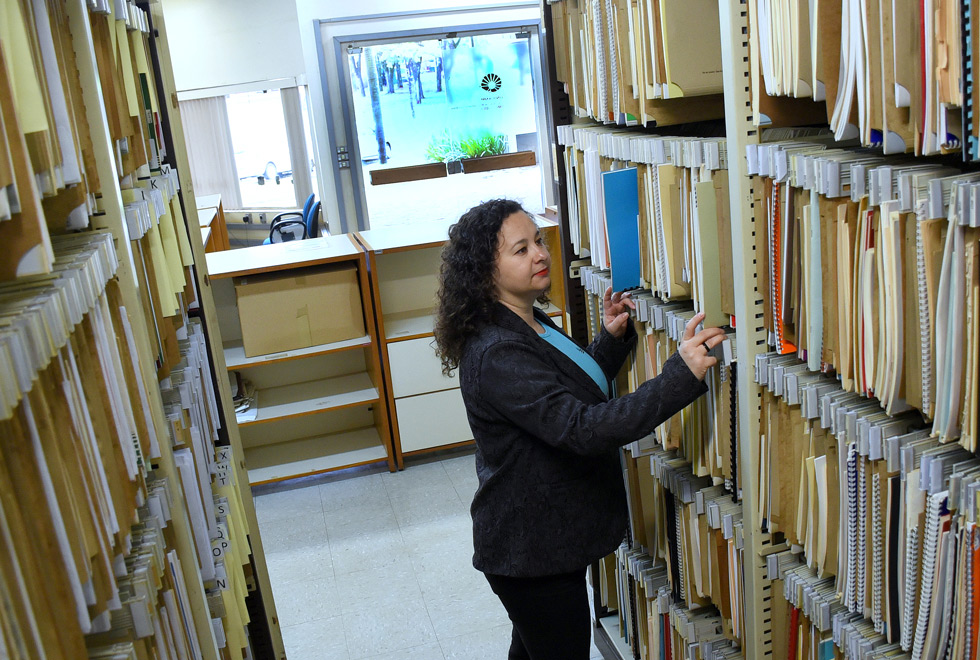 Em meio ao acervo da Coordenação de Documentação em Música Contemporânea, a bibliotecária Fabiana Benine mexe nas pastas de partituras. 