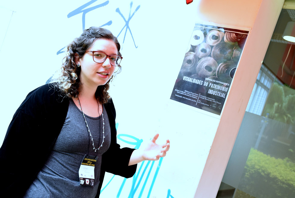 Elisa Pomari, doutoranda em História na Unicamp, mostra o cartaz da exposição fotográfica 