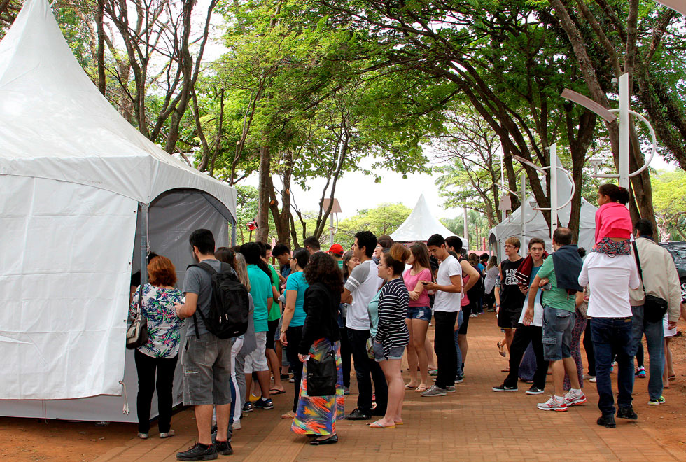 Publico do evento está em pé em frente a uma das tendas de comida