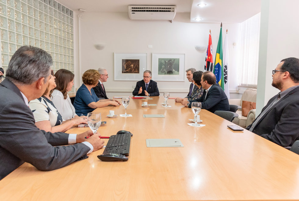 Imagem de todos os presentes sentados ao redor da mesa de reunião no GR