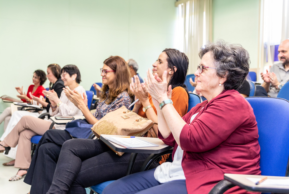 Plateia aplaude falas de pesquisadoras durante evento sobre gênero e trabalho