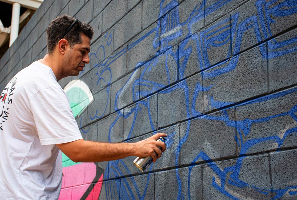 Angelo Bueno, grafiteiro, realiza trabalho em parede da Diretoria Geral da Administração