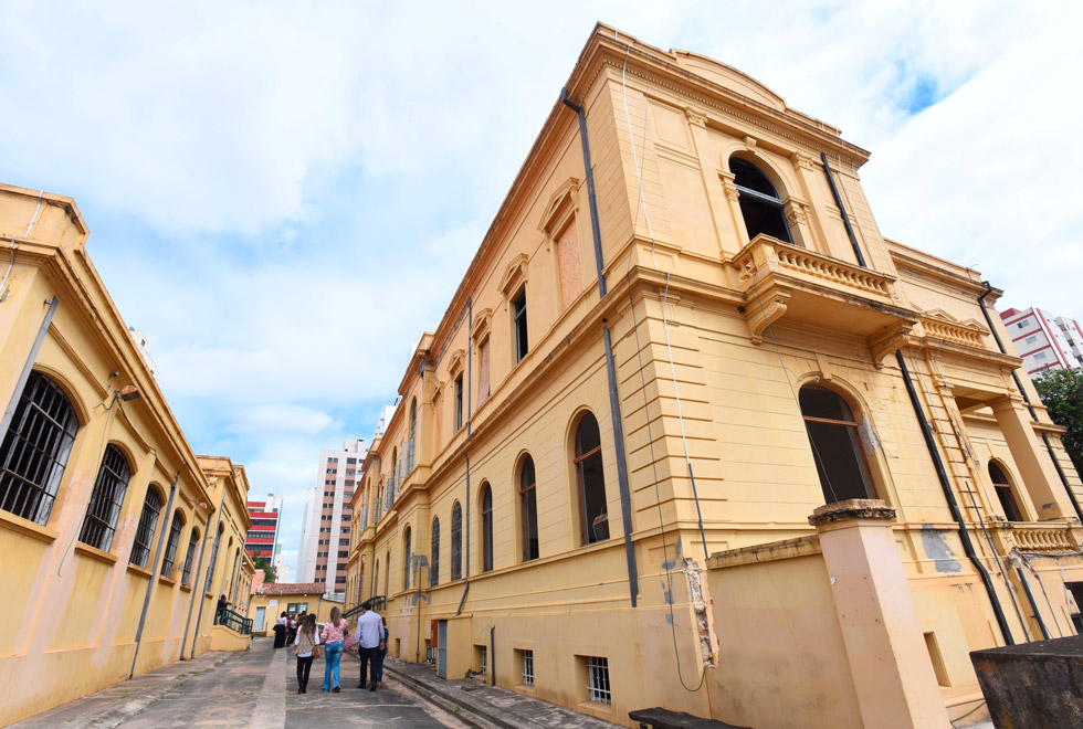Audiodescrição: fotografia colorida mostra fachada de prédio histórico, na cor amarela