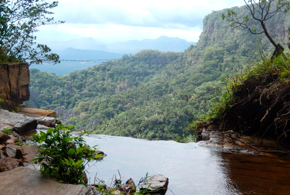 A imagem mostra o topo de uma cachoeira com muito verde em volta e ao fundoloresta úmida de brejo de altitude na área de abrangência da Caatinga no Parque Nacional de Ubajara (CE).