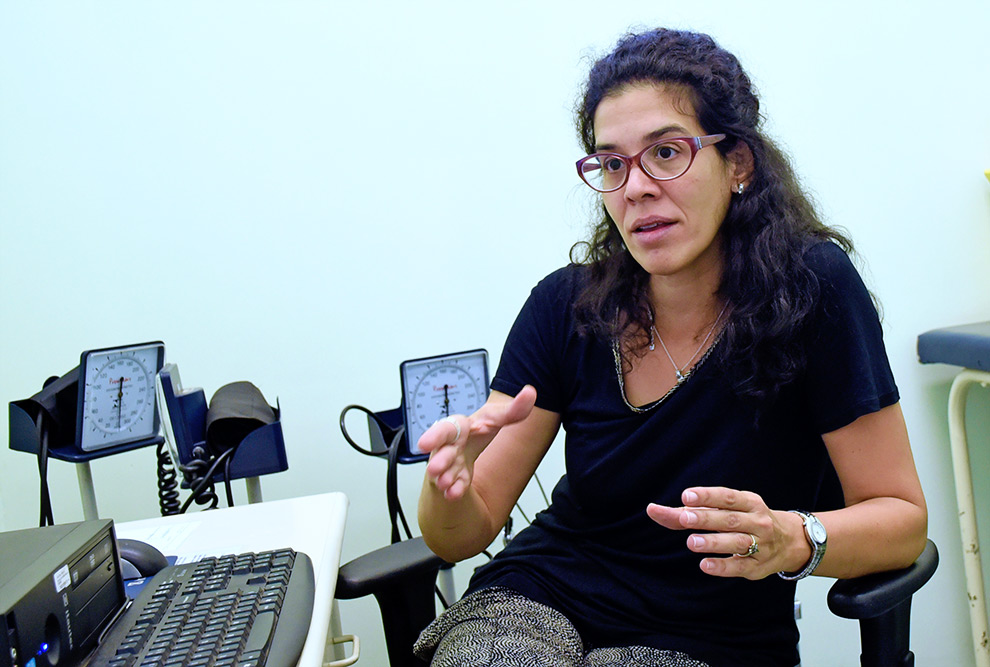A psiquiatra Karina de cabelos compridos em parte presos, de óculos e blusa preta durante entrevista em um consultório da FCM