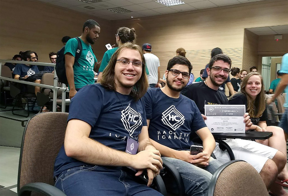 Vencedores da competição, são três rapazes sentados com a camiseta do evento e uma garota mostrando um diploma da premiação