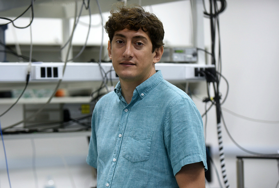 De camisa azul Thiago posa para foto no laboratório