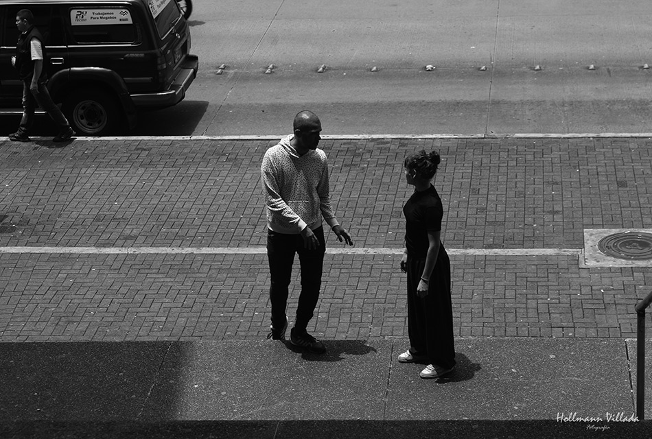 Um homem e uma mulher se encontram em uma calçada na imagem do espetáculo apresentado pelo artista. Eles parecem conversar