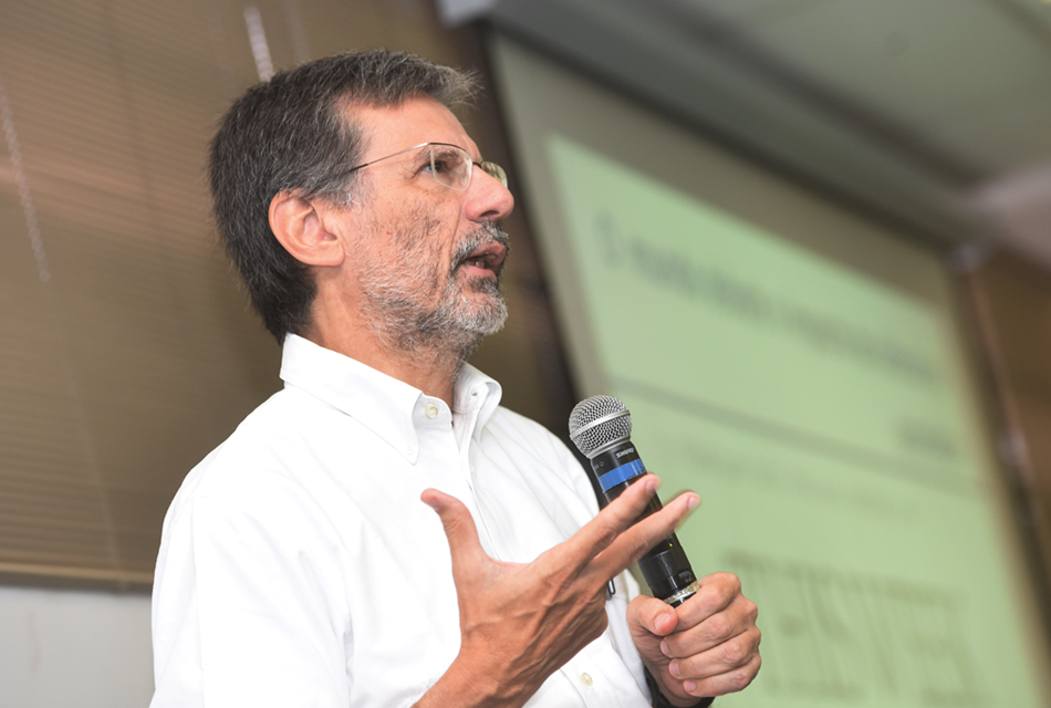 Homem de camisa branca e barba fala ao microfone