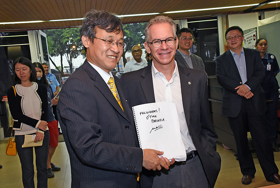 O reitor Marcelo Knobel posa para fota com o diretor chines do Instituto Confucio. Eles mostram um papel onde está escrito "felicidades, ótima parceria", assinado por Knobel