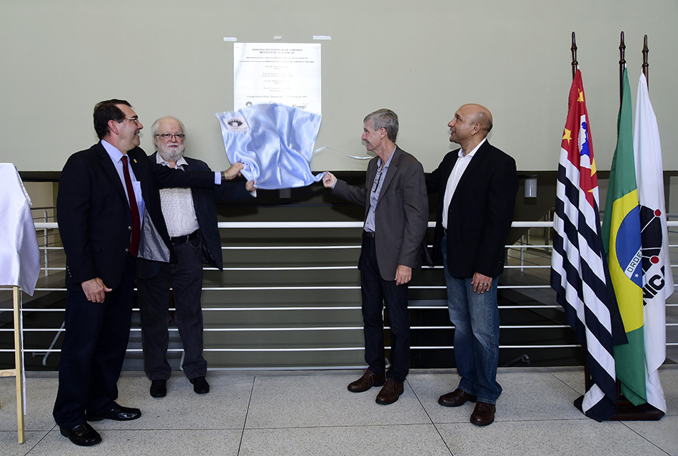 Autoridades fazem o descerramento da placa inaugural. Eles observam o tecido sendo retirado da placa.