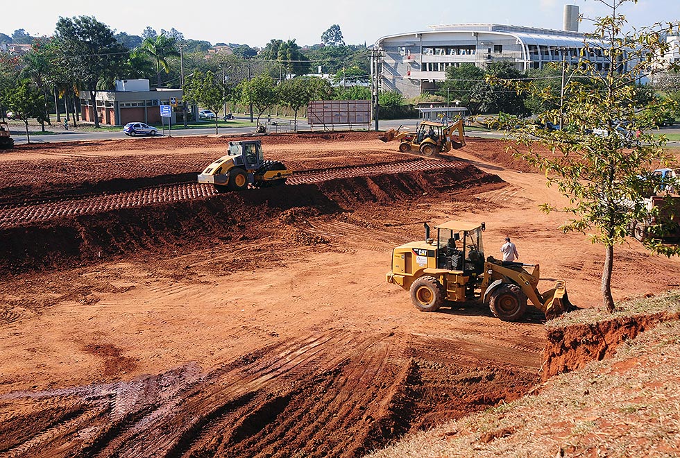 caminhões trabalham no início das obras do teatro do IA, três caminhões aparecem fazendo a terraplenagem