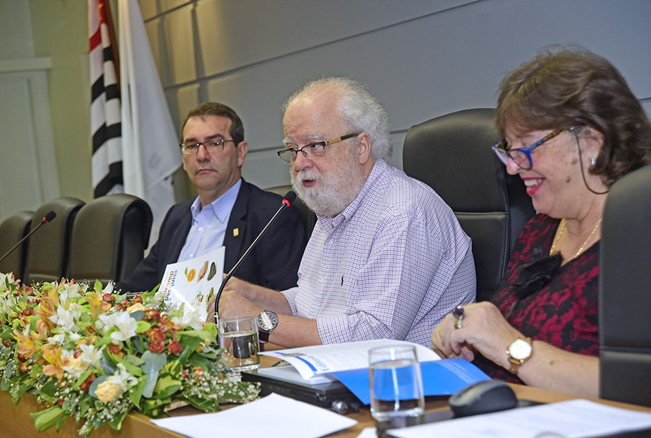 Reitor José Tadeu Jorge ao centro da mesa folheia a revista ao lado dos professores Alvaro Crósta e Gláucia Pastore