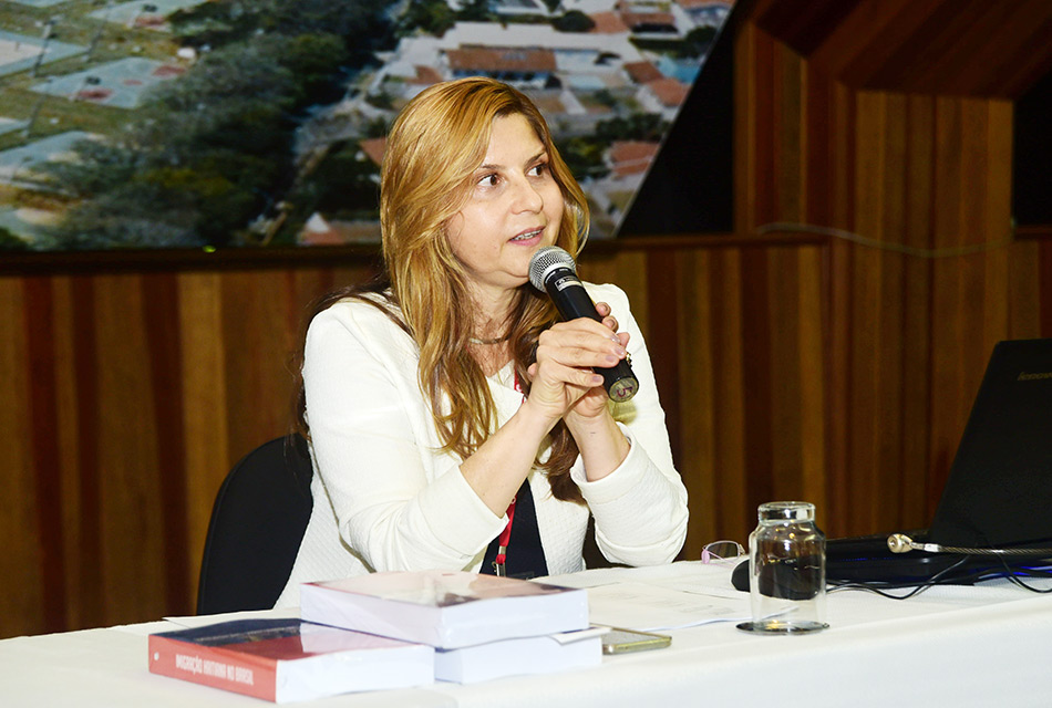 Professora Rosana Baeninger com microfone na mão fazendo a palestra