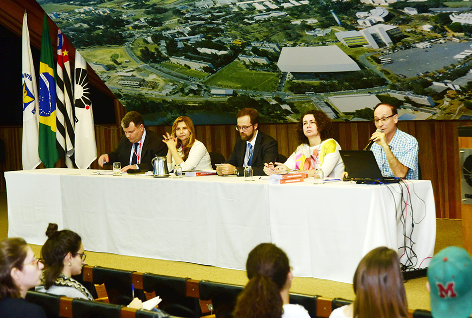 Palestrantes sentados à mesa de abertura do evento