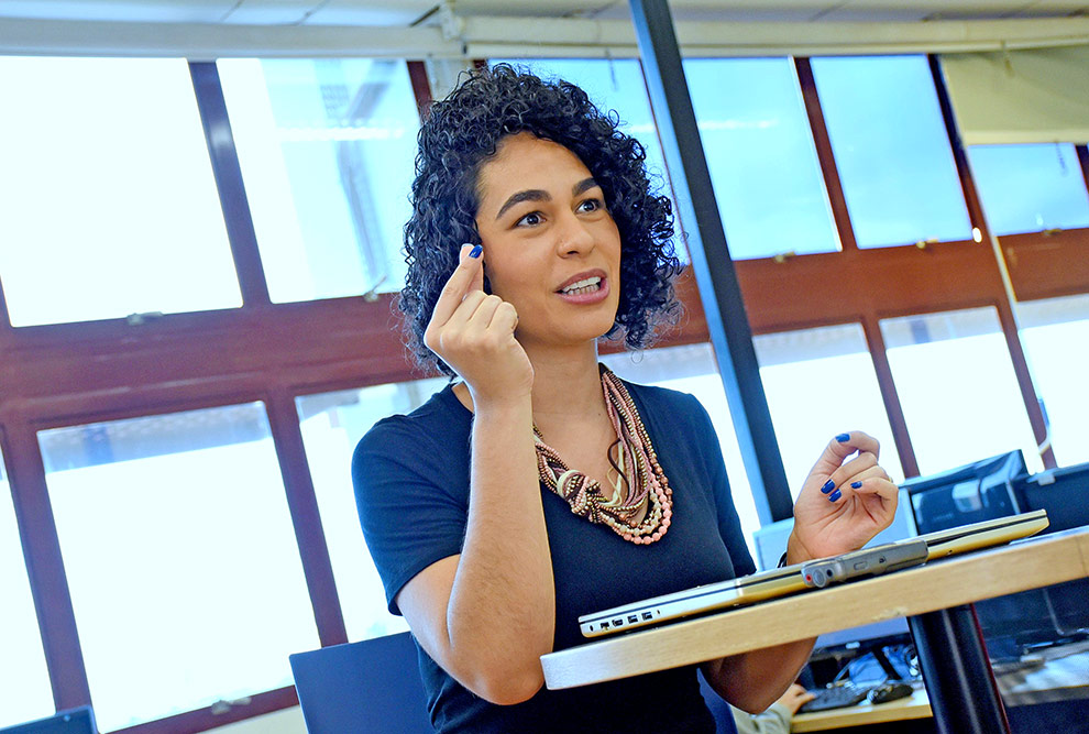 audiodescrição: fotografia colorida da professora Sandra Avila em momento de entrevista, ela está gesticulando e sentada ao redor de uma mesa