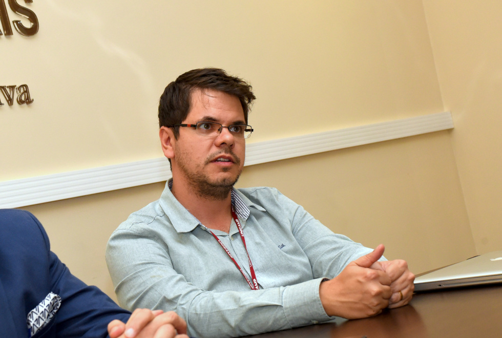 foto mostra o professor josé luiz módena sentado à mesa falando