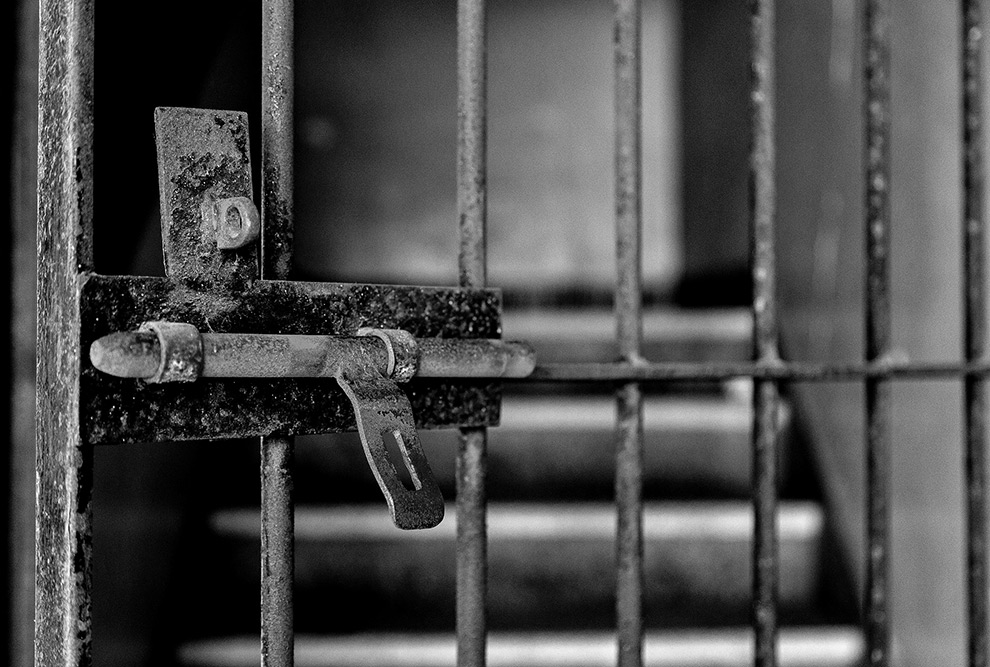 audiodescrição: fotografia preto e branco de detalhe da porta de uma cela
