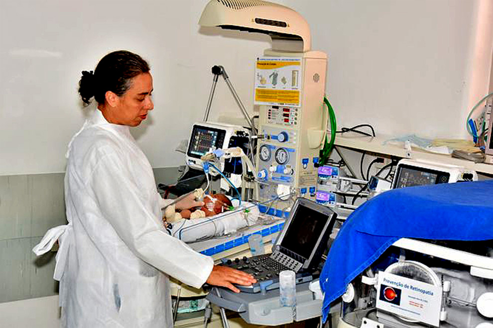 foto mostra médica examinando um bebê na UTI neonatal