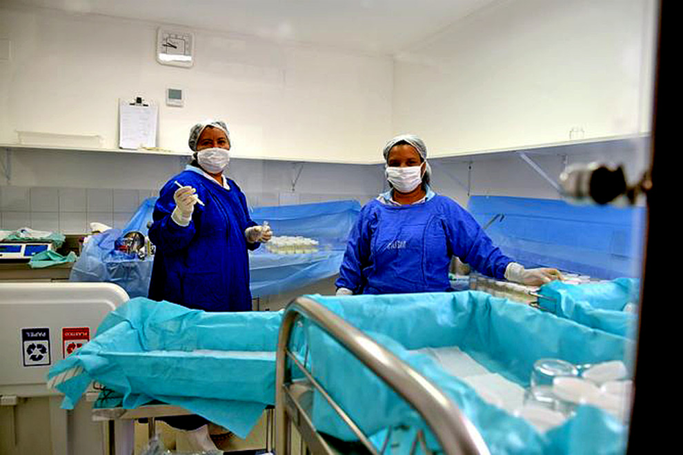 foto mostra duas enfermeiras paramentadas com roupas de proteção contra contaminação