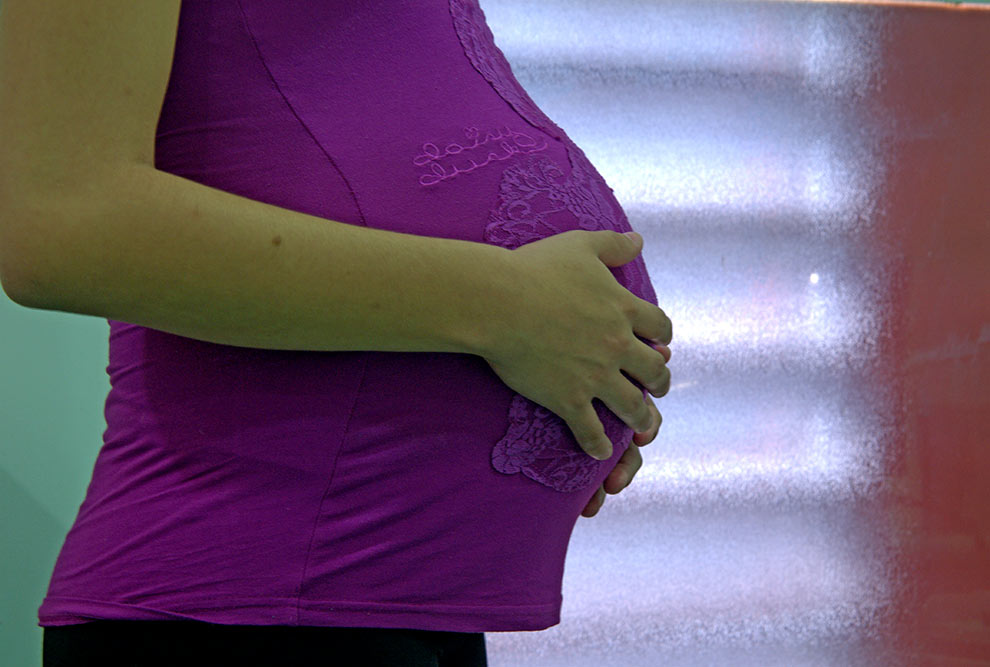 foto mostra uma mulher grávida passando a mão em sua barriga