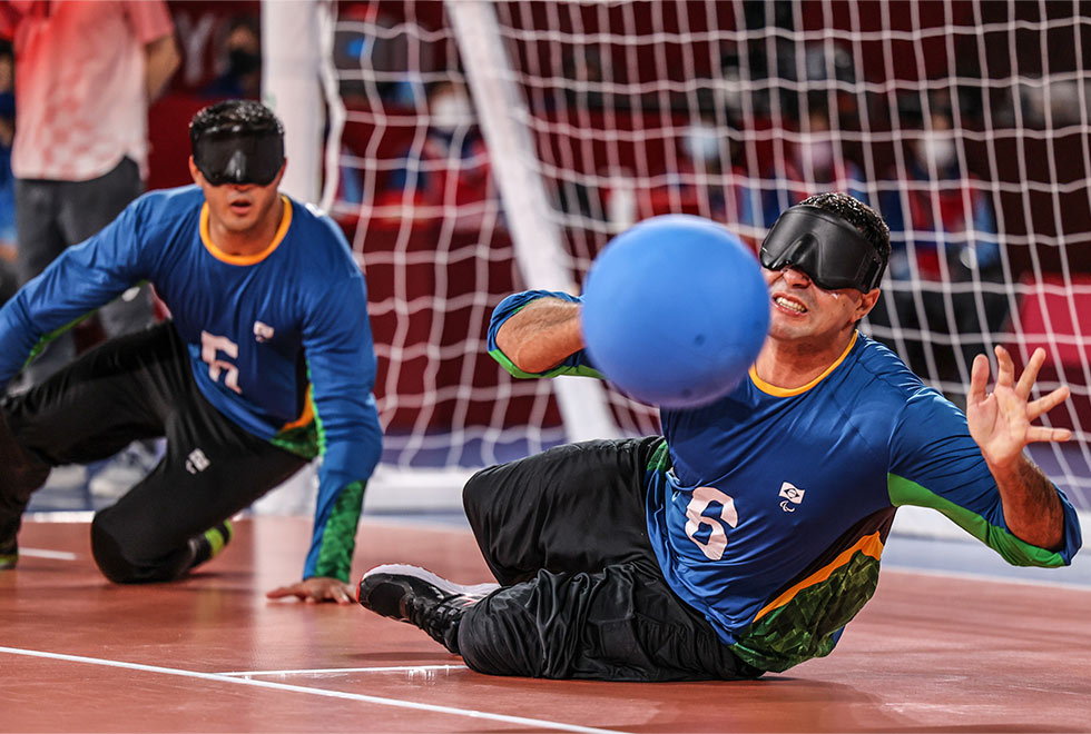 foto mostra jogador no chão da quadra recebendo uma bola jogada ao gol