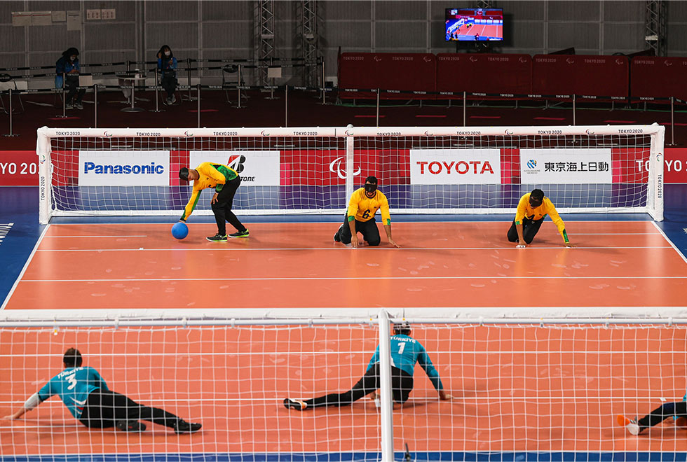 foto mostra uma quadra de goalball com os jogadores posicionados na frente do gol