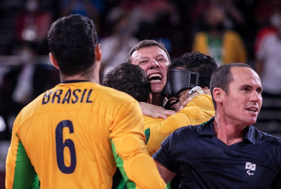 foto mostra alessandro comemorando vitória abraçado com outros jogadores