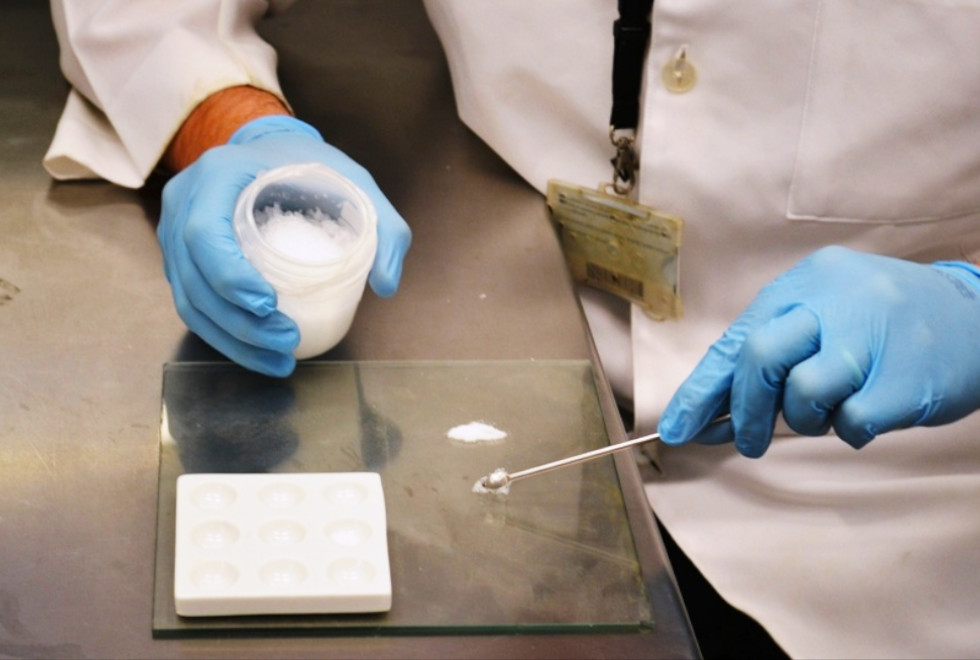 imagem mostra pesquisador manuseando drogas sintéticas com instrumentos