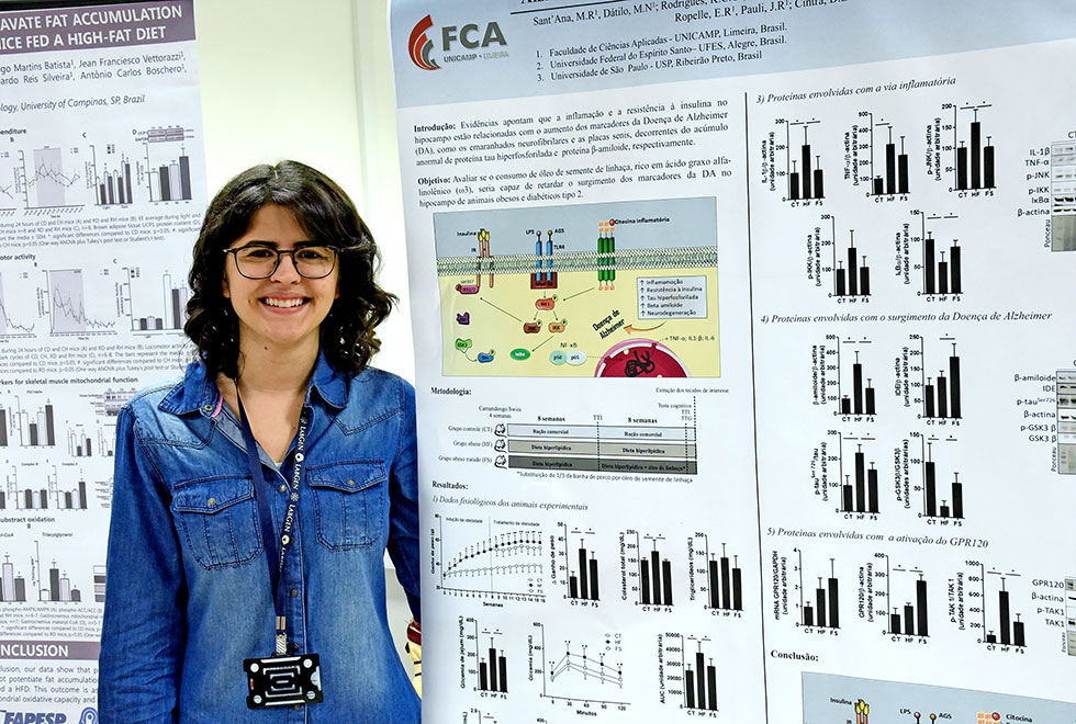 Marcela aparece ao lado do poster com informações sobre sua pesquisa