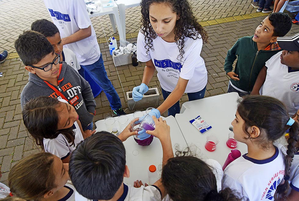 crianças observam experimento de quimica