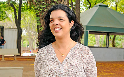 Daniele Maia Rodrigues: 83 mil grafos por time em cada tempo de jogo Audiodescrição: Em área externa, uma praça, mulher em pé, em imagem frontal e de busto, sorri, sendo que ela encontra-se em local com várias árvores de grande porte ao redor, bancos de concreto e um quiosque com teto de lona verde ao fundo. Ela veste blusa com gola V e usa um colar com pingente.