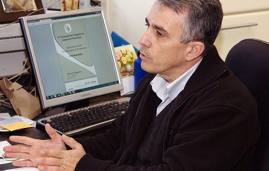 O professor Marco Aurelio Zezzi Arruda, do Instituto de Química, onde foram feitas análises | Foto: Isaías Teixeira Audiodescrição: Em sala de trabalho, imagem em perfil e close-up, homem sentado em cadeira, ao centro na imagem e com olhar voltado para a esquerda, se comunica falando. À frente dele, há um monitor de lcd em funcionamento sobre uma suposta mesa. Ele veste blusa preta sobre camisa social branca. Imagem 1 de 1.