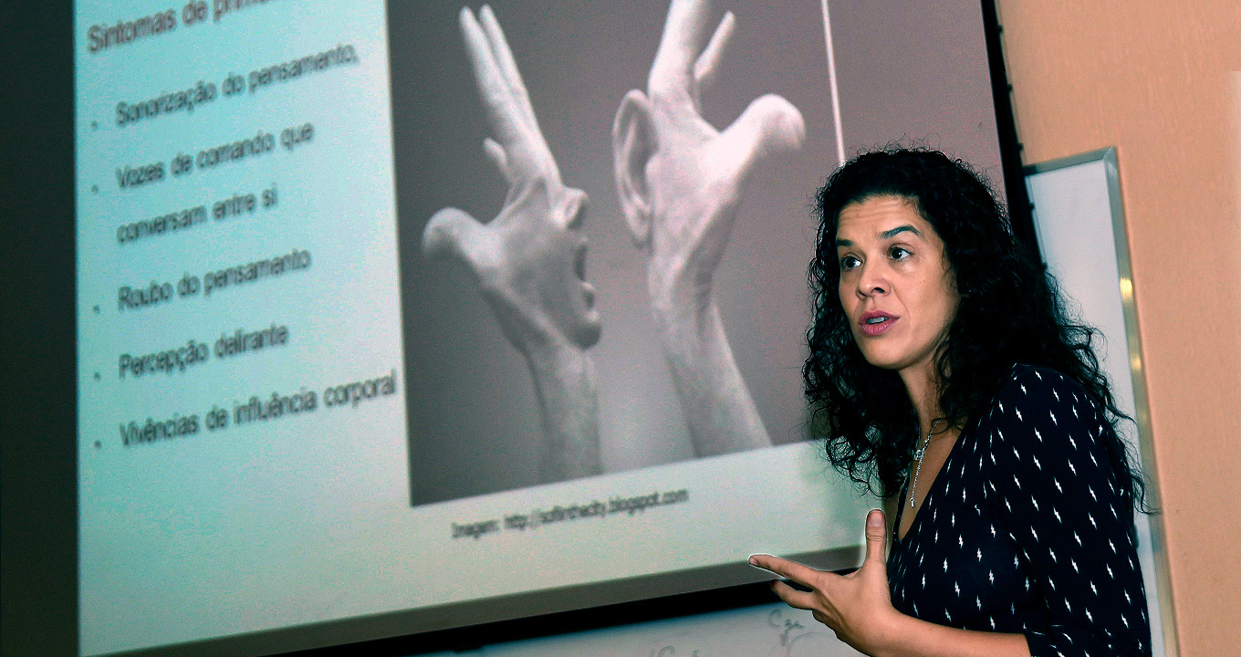 Karina Diniz Oliveira, professora da FCM, fala durante palestra | Foto: Antonio Scarpinetti Audiodescrição: em auditório, imagem de busto e em perspectiva, mulher com olhar voltado para a esquerda da imagem fala e gesticula com a mão esquerda, mantendo o braço dobrado e esticado para frente, com a palama da mão aberta e voltada para cima. Às costas dela, à esquerda, ampla tela de projeção de data show afixada na parede, onde se lê em destaque frase como sonorização, vozes de comando, entre outras, ao lado de uma imagem em preto e branco com montagem de dois braços com orelha e face. Imagem 1 de 1.