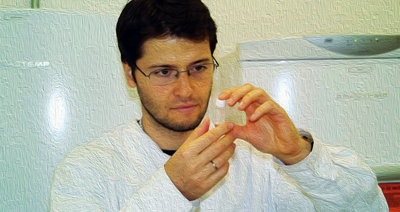 foto mostra filipe vagas em um laboratório com uma ampola nas mãos olhando para ela
