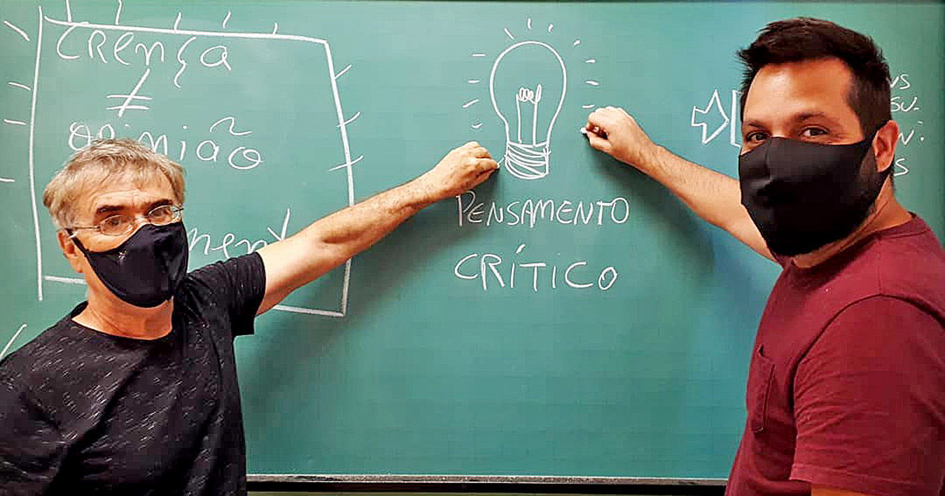foto mostra professores membros do projeto escrevendo na lousa "pensamento crítico"